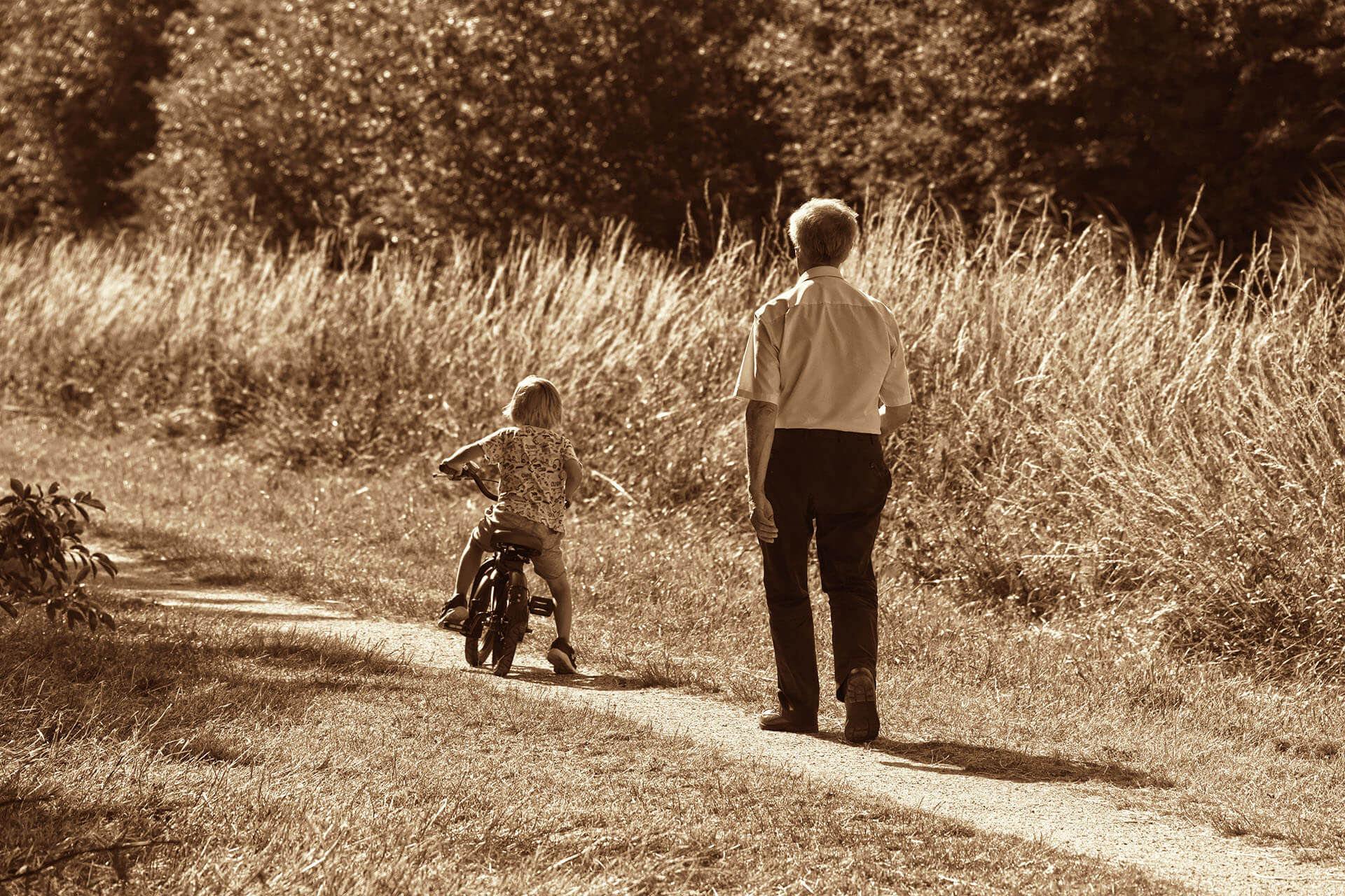 un vecchio che insegna ad un bambino ad andare in bicicletta